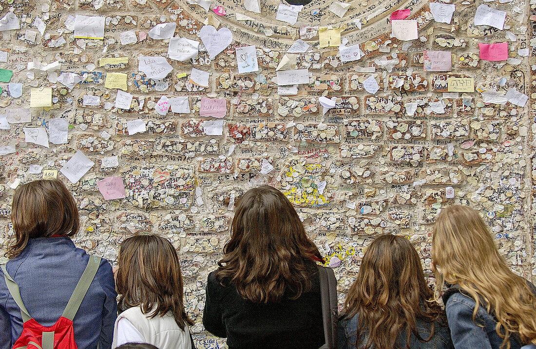 Teenager-Mädchen betrachten Schriftzeichen an den Wänden des Innenhofs von Juliet s House. Verona. Venetien, Italien