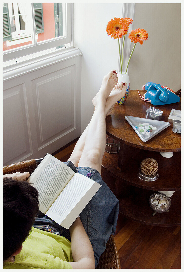  Absorbed, Adult, Adults, At home, Barefeet, Barefoot, Book, Books, Calm, Calmness, Color, Colour, Comfort, Comfortable, Contemporary, Daytime, Female, Flower, Flowers, Full-body, Full-length, Home, Human, Indoor, Indoors, Interior, Leisure, Literature, L