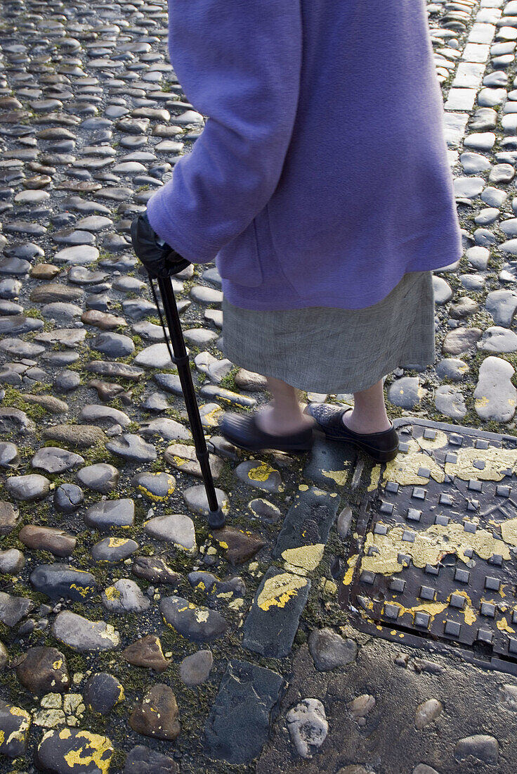  Adult, Adults, Aged, Anonymous, Cane, Canes, Cobble, Cobbles, Coblestone, Coblestones, Color, Colour, Contemporary, Daytime, Detail, Details, Difficult, Difficulty, Elderly, Exterior, Female, Ground, Grounds, Human, Leg, Legs, Mature adult, Mature adults