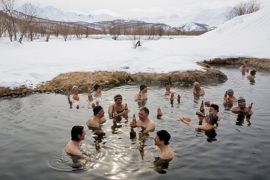 Eine Gruppe Männer beim Baden in einer heissen Quelle, sie trinken ein Bier, Winter in Kamtschatka, Sibirien, Russland