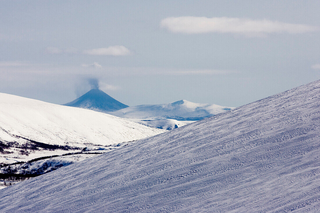Winter in Kamtschatka, Sibirien, Russland, Ausbruch des Vulkans Karymsky, Asche bedeckt die Flanken des Vulkanes