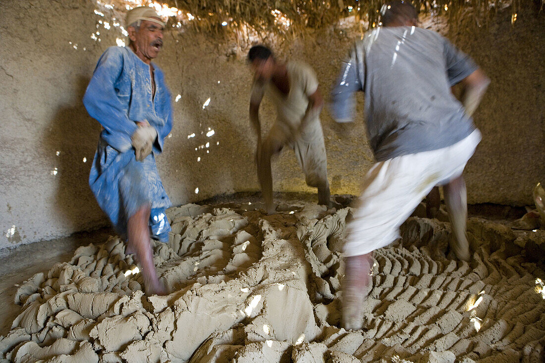 Men kneading argile with their foot while singing raucously in a weird choregraphy. Ancestral pottery workshop near Maruza, between Qena and Luxor, using locally extract argile. Egypt
