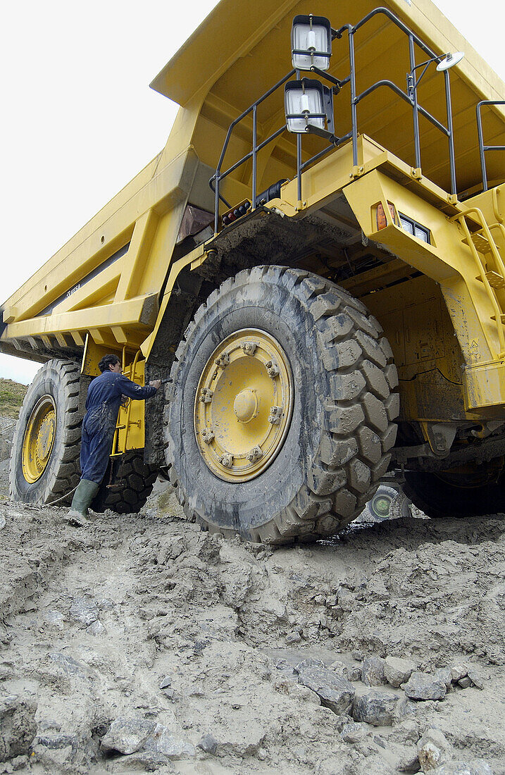 Worker cleaning dumper-truck to carry marl from quarry to cement plant