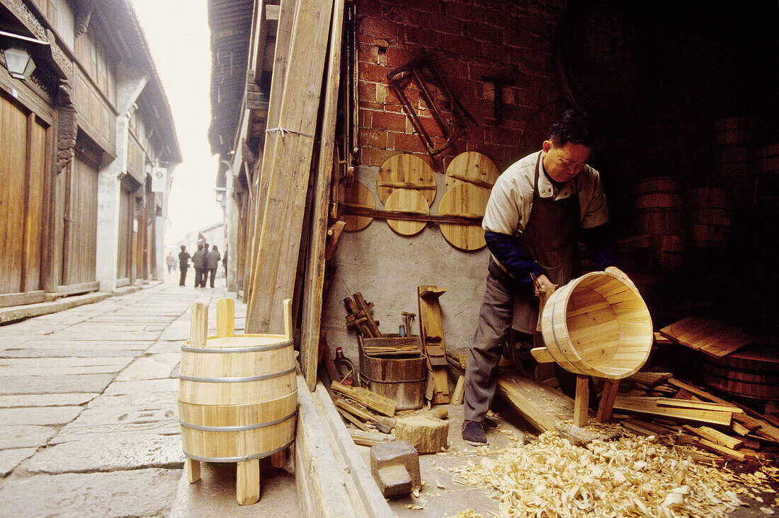 Wood barrels maker at work in the main street. Wushen, small historic city with many canals. Zhejiang province, China