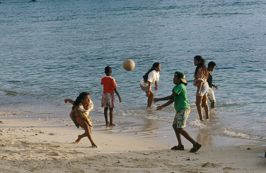 Children playing on a beach at dusk. Victoria, the capital. Mahe Island. Seychelles archipelago. Indian Ocean.