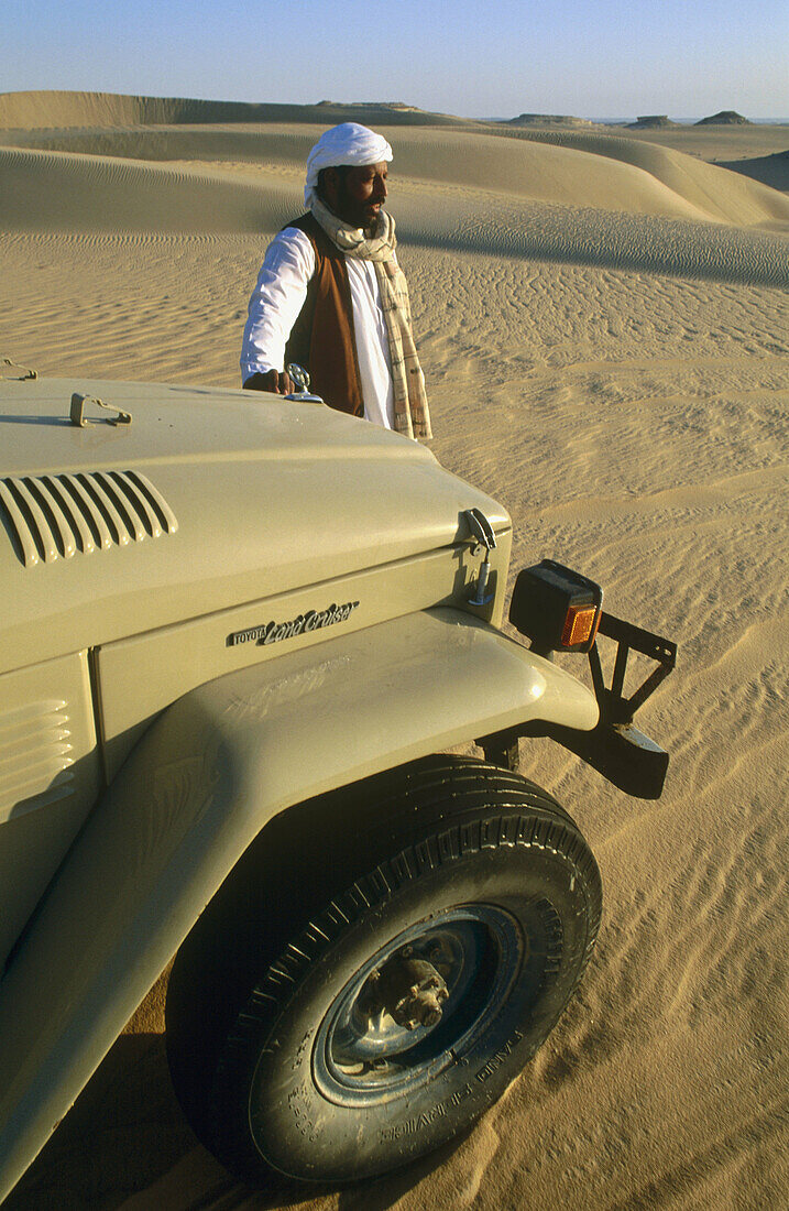 Bedouin wearing the traditional local costume in front of the Great Sand Sea, Lybian desert, Siwa Oasis. Egypt