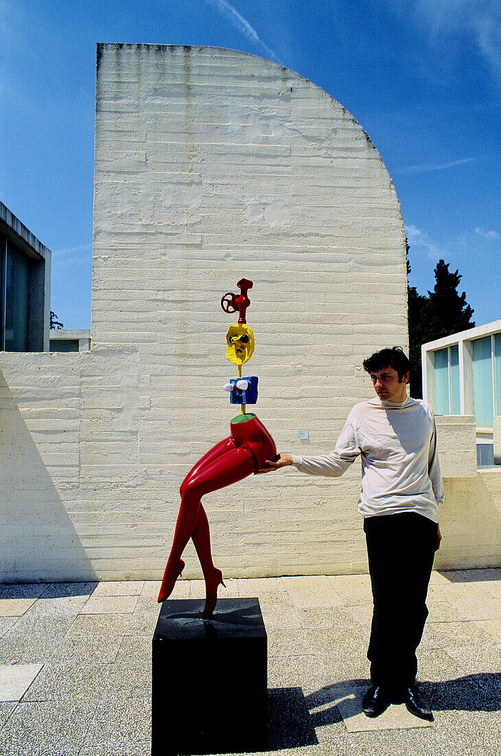 Man petting irrevently a sculpture in Joan Miró Foundation. Barcelona. Spain