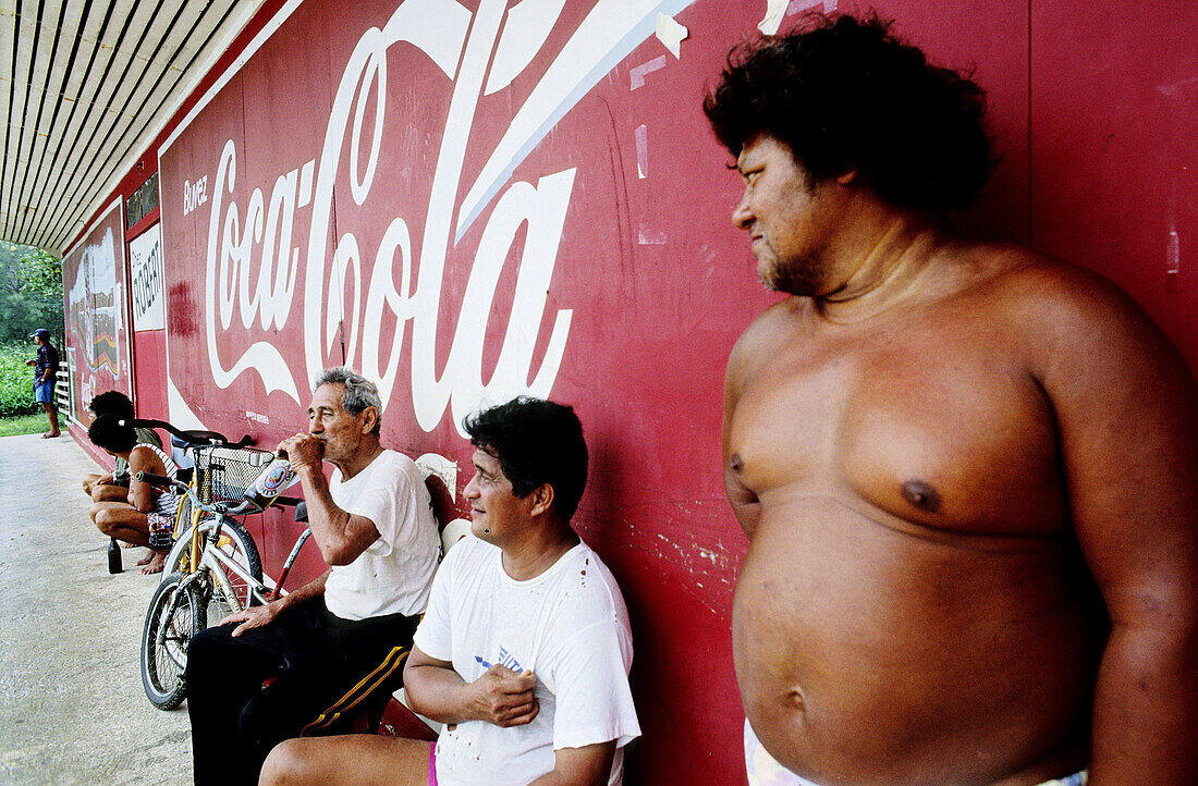Idle men drinking beer out of a chinese grocery in Moorea island in the Windward islands. Society archipelago. French Polynesia