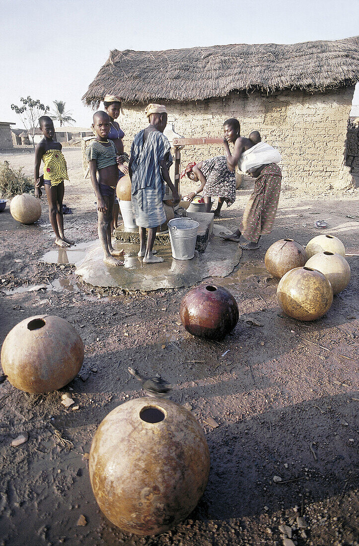 Women taking water at the village pump using calabashes. Senufo Country. North Ivory Coast