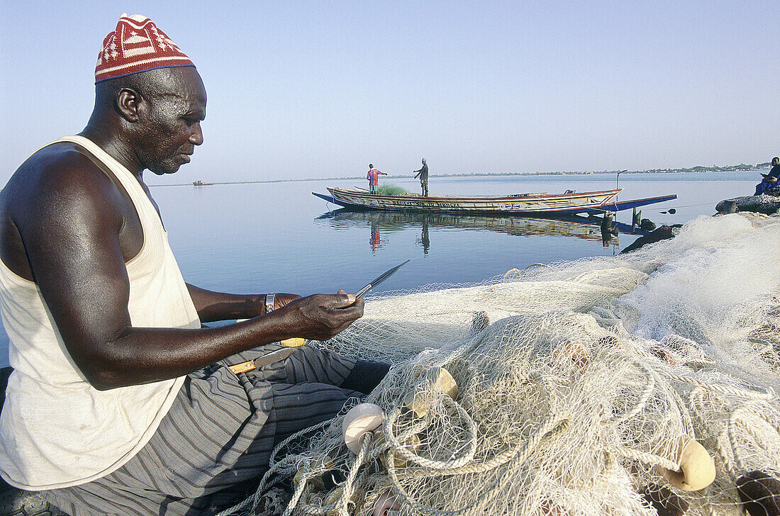 Fisherman mending his nets at the seashore. Foundiougne. Sine Saloum province. Senegal
