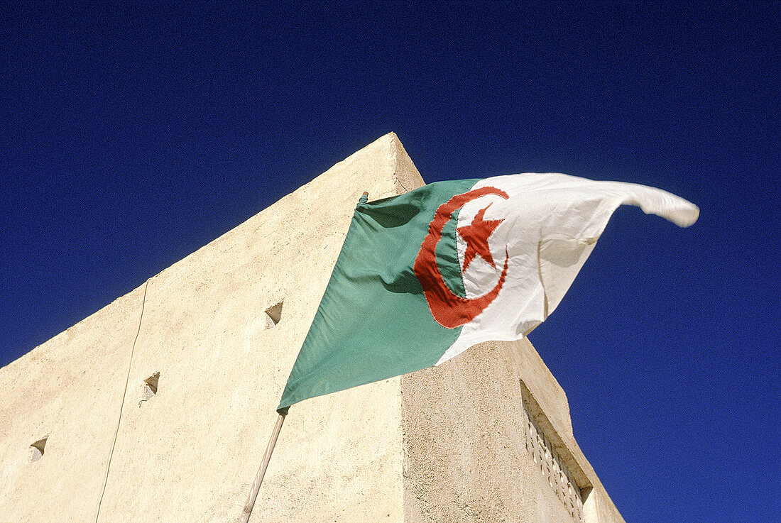 Algerian flag on the top of an ancient adobe mosque. Guardaia oasis. Sahara. South Algeria