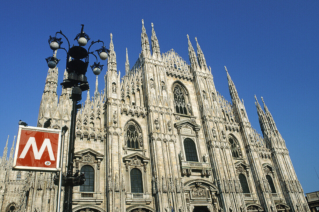 Main facade of the Duomo and subway entrance sign. Milan. Italy