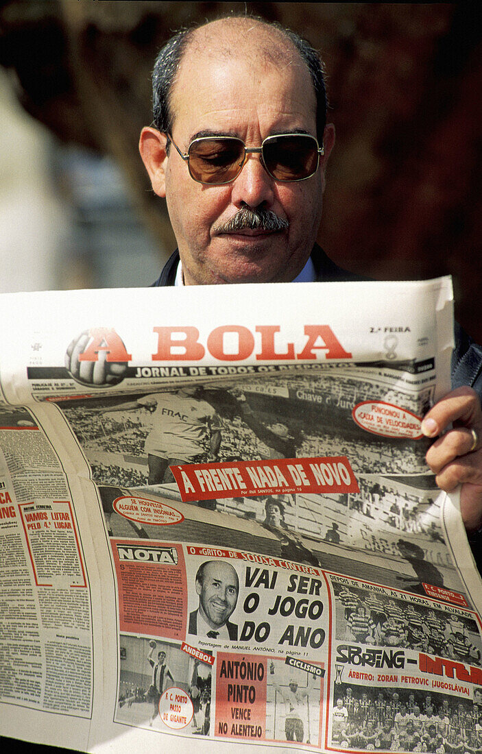 Man reading A Bola newspaper specialised in football. Lisbon. Portugal