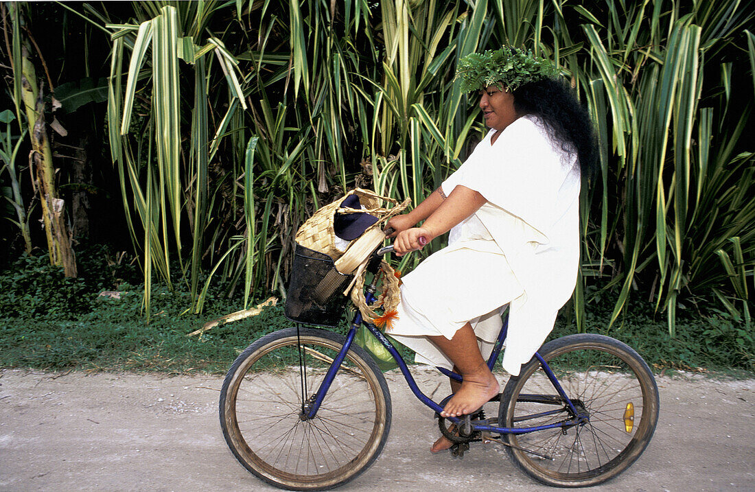 Woman cycling. Moorea, Windward Islands. French Polynesia