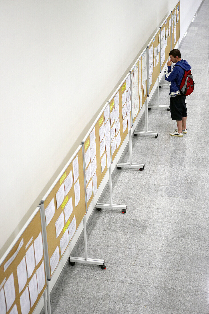 Student looking at notice board. Escuela Universitaria Politecnica, UPV (Universidad del Pais Vasco), Campus de Gipuzkoa. San Sebastián, Euskadi, Spain