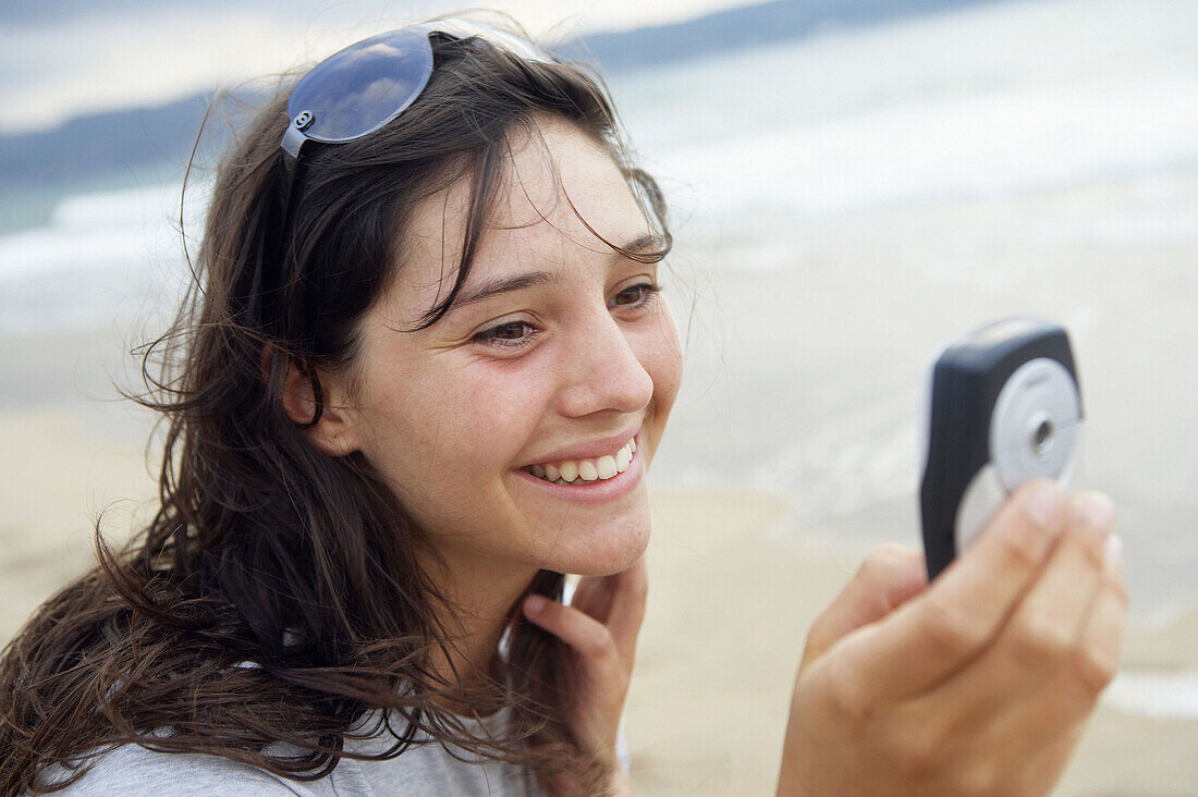 16 Jahre altes Teenie-Mädchen benutzt Handy am Strand