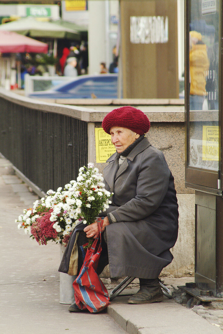 Moscow, Russia, old woman with winter hat and coat sellling bouquets of flowers on street.