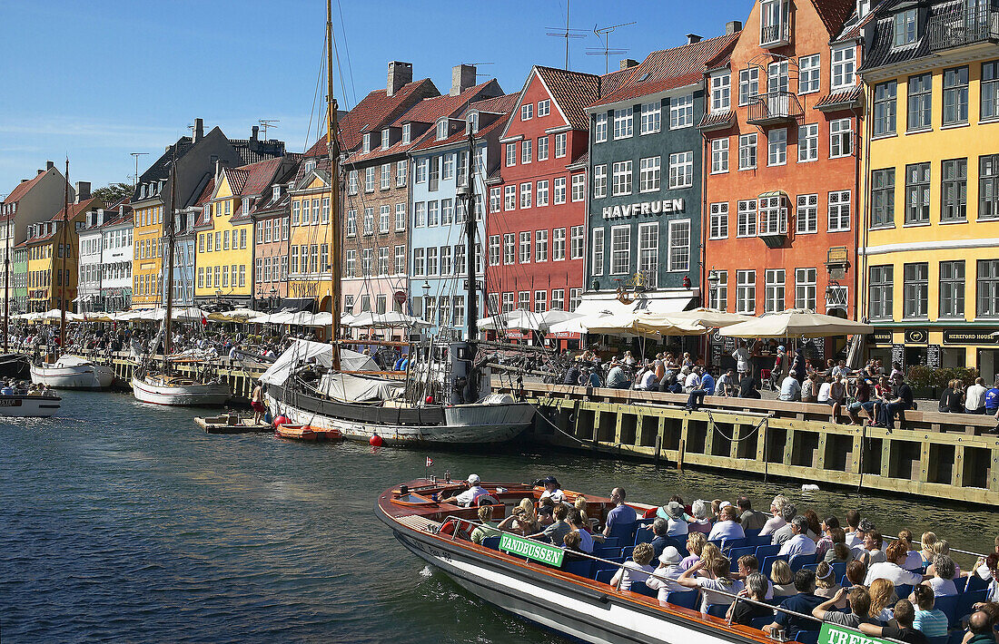 Tour boats, moored sailboat, ancient houses and waterfront cafe terraces at Nyhavn ( New Harbor ), Copenhagen. Denmark