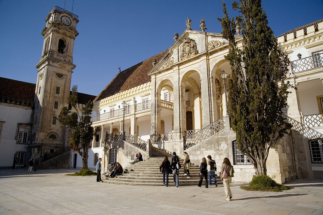 Coimbra, Portugal: Students in the inner core of the University of Coimbra in front of steps leading to cloistered arcade, Via Latina. The University was established in 1537. Note the famous curfew-signaling clock of Coimbra...