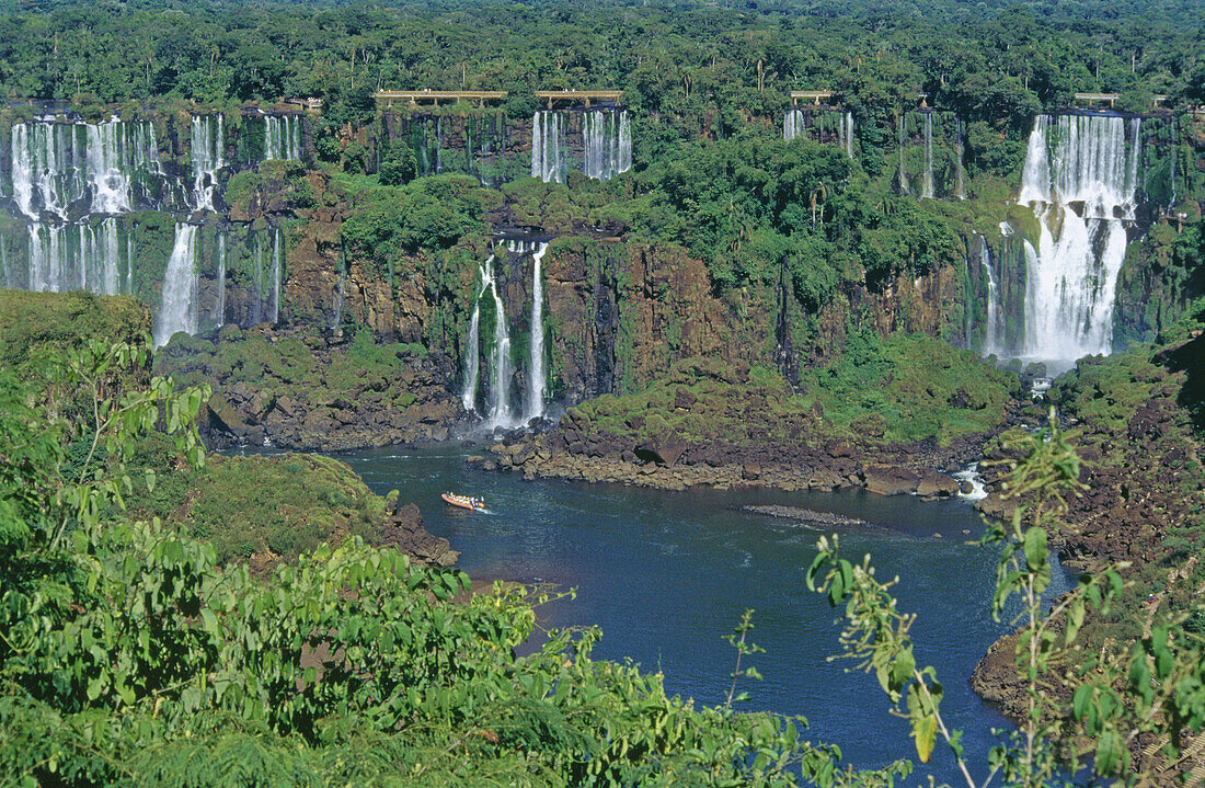 Rubber dinghy with tourists sailing on the Iguazu river, the Falls at the rear. Iguazu National Park. Misiones province. Argentina.