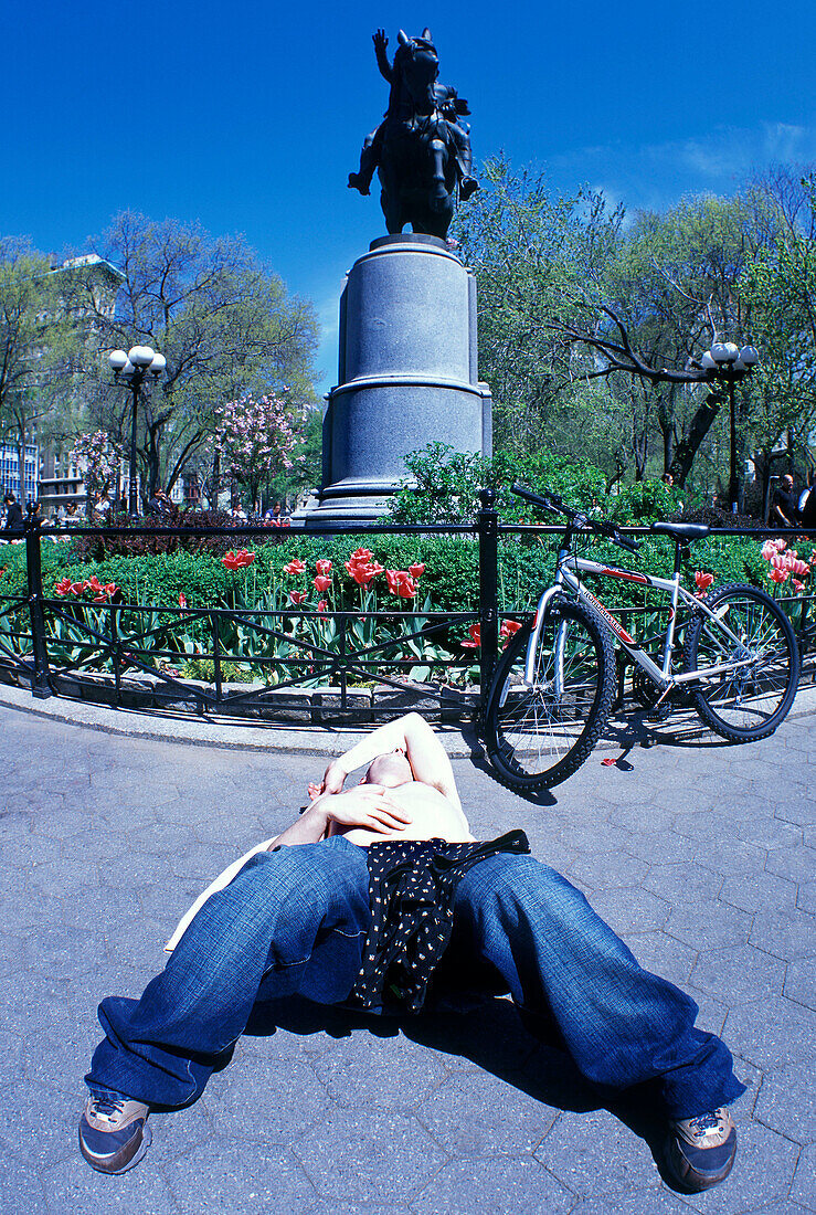 young man lying on pavement, Union square, Manhattan, New York, USA