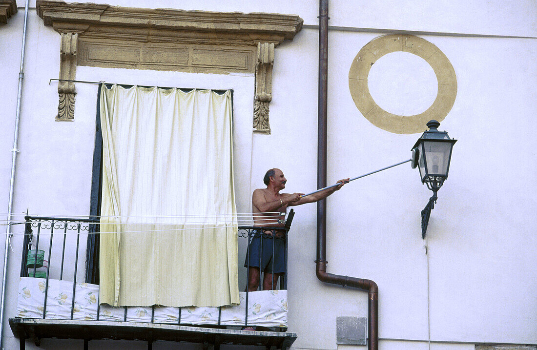 Man cleaning street lamp. Palermo. Sicily. Italy