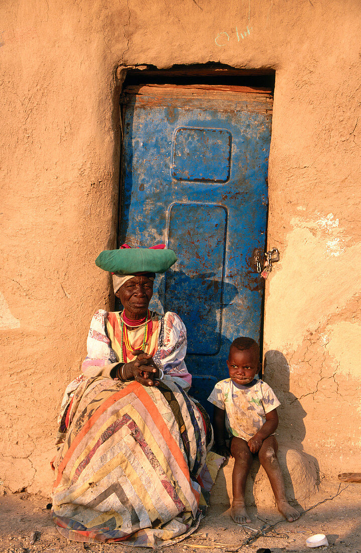 Traditionally dressed Herrero woman and grandson at their house. Warmquelle village. Southern Kaokoveld. Namibia