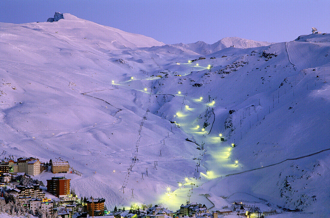 Snowy January landscape in Solynieve skiing resort by Pico Veleta, Sierra Nevada: the central run is illuminated only in Saturday evenings. Granada province, Andalusia, Spain