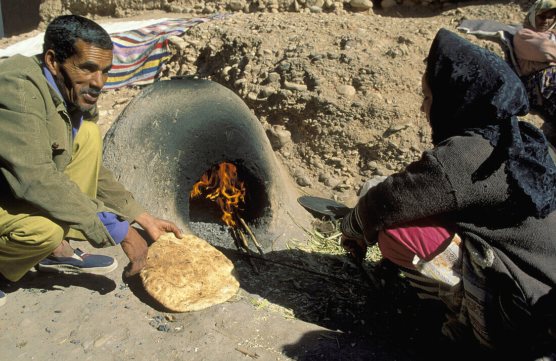 A Berber woman bakes bread at a public square inside the kasbah (fortress) Taourirt in the town of Ouarzazate, south of the High Atlas mountains. Southern Morocco.