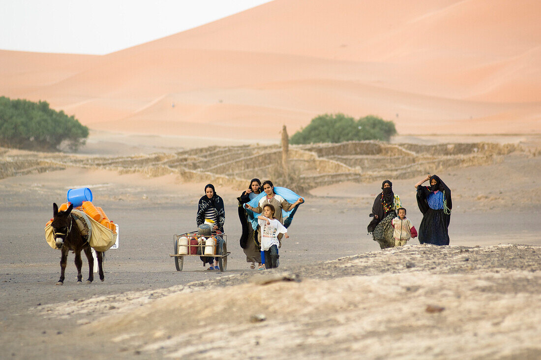 Gruppe Frauen und Kinder mit Esel in der Wüste, Erg Chebbi, Marokko