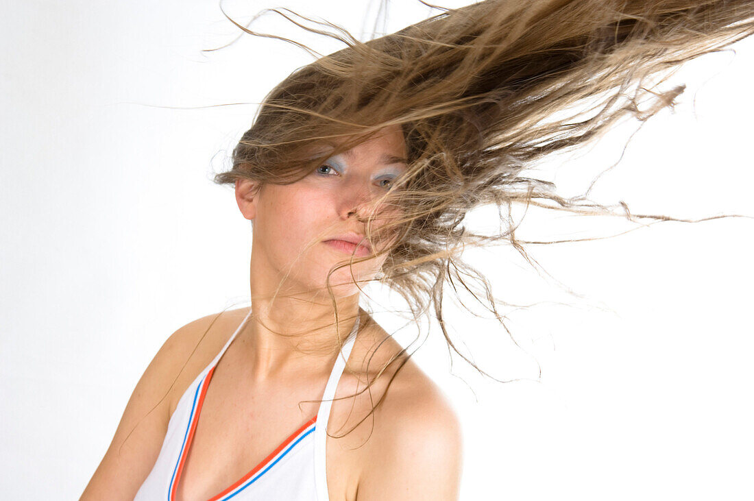 Young woman swirling her hair through the air, wind