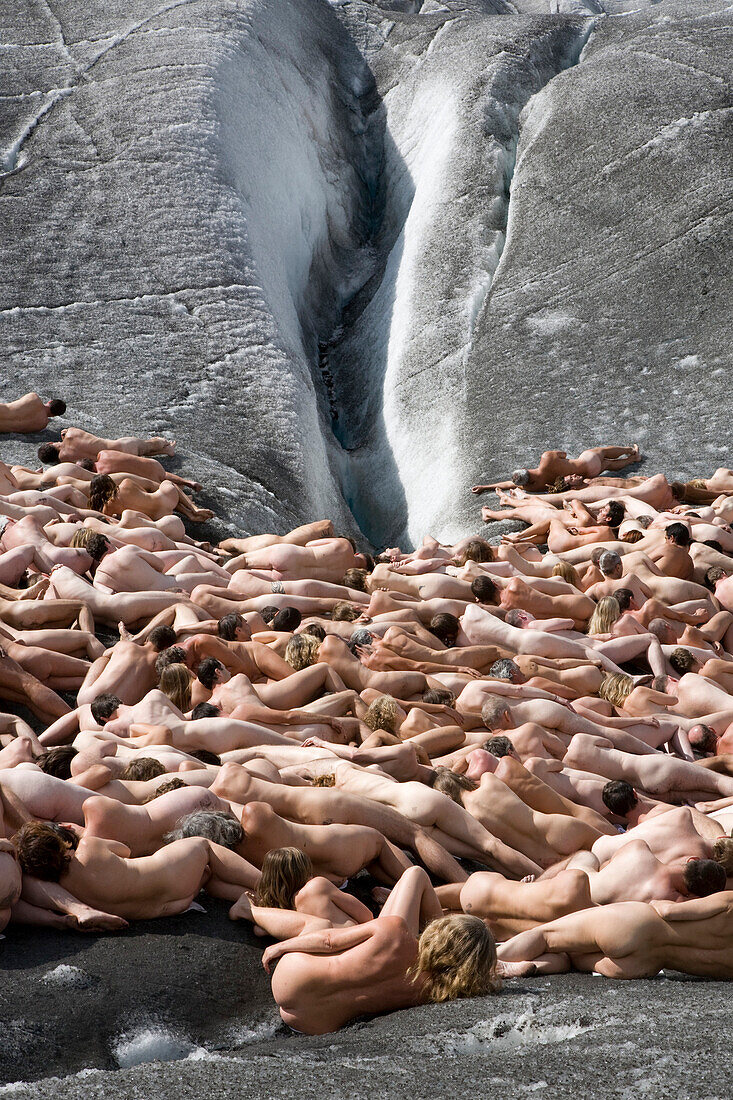 A group of naked people lying on the ice in front of an ice crevasse, around 600 people are posing for Spencer Tunick and Greenpeace on the Aletsch Glacier to protest about climate change, Aletsch Glacier, Valais, Switzerland