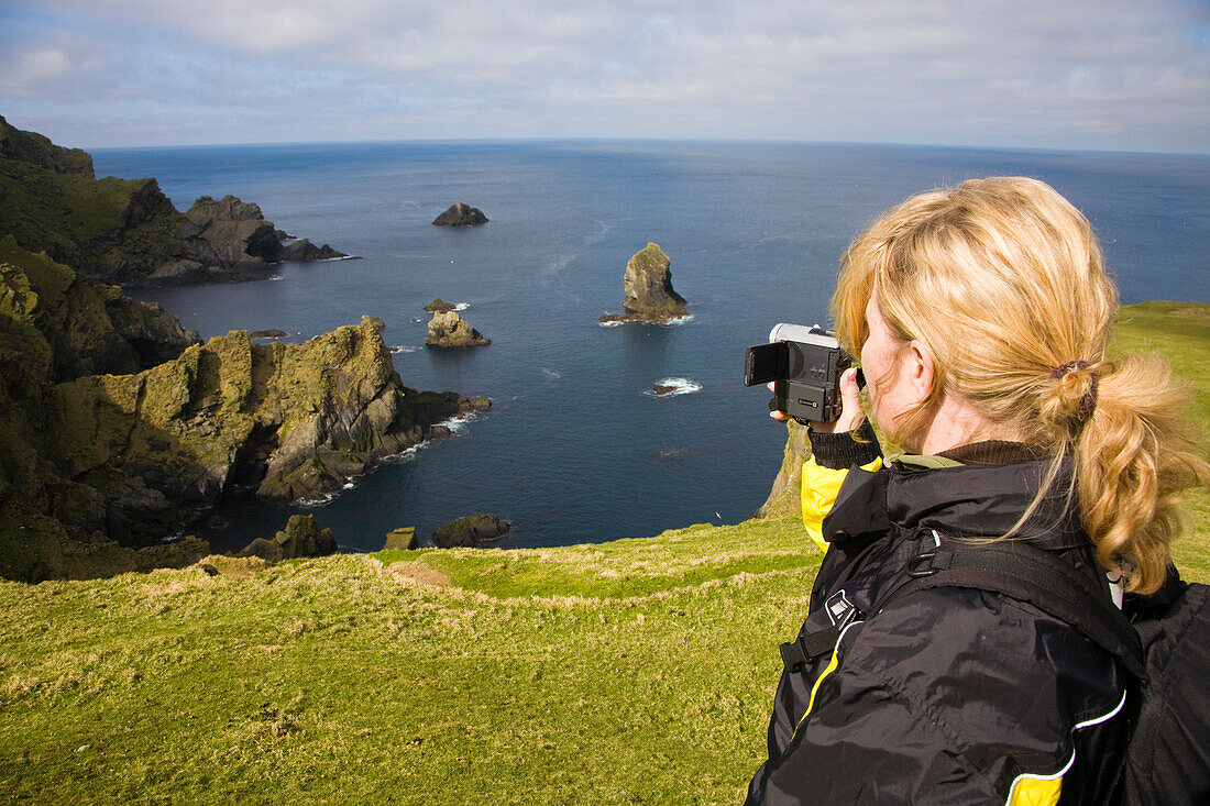 Eine Frau filmt die wilde Küste des Naturschutzgebietes Hermaness, Insel Unst, Shetland Islands, Schottland, Großbritannien, MR