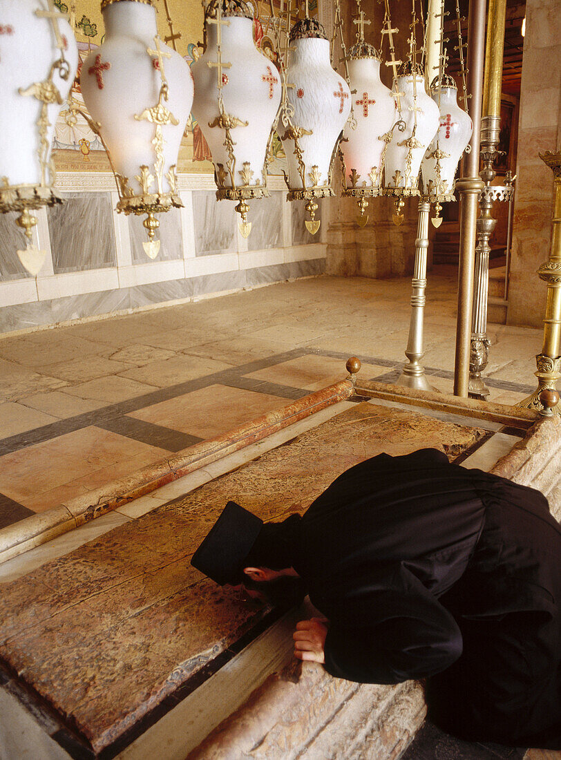 Monk kissing the Stone of the Anointing, believed to be the place where Jesus body was prepared for burial in the Church of the Holy Sepulchre, Jerusalem. Israel