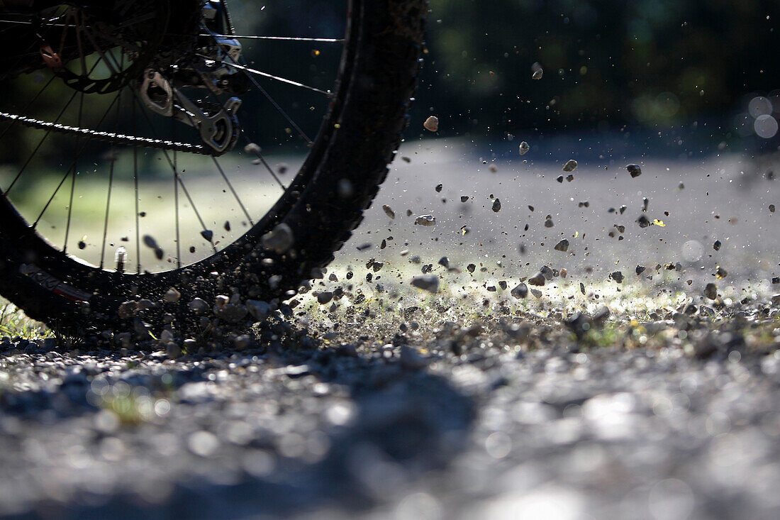 Rad von einem Mountainbike wirbelt Schotter auf, Oberammergau, Bayern, Deutschland