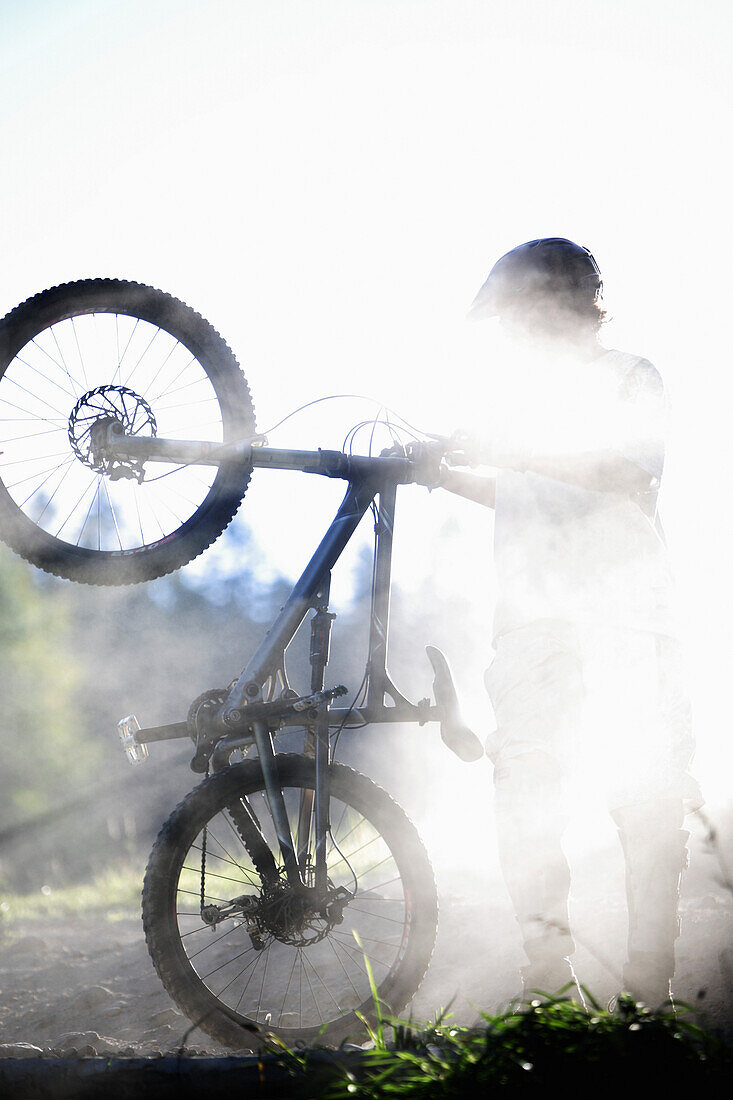 Young man holding a mountain bike, Oberammergau, Bavaria, Germany