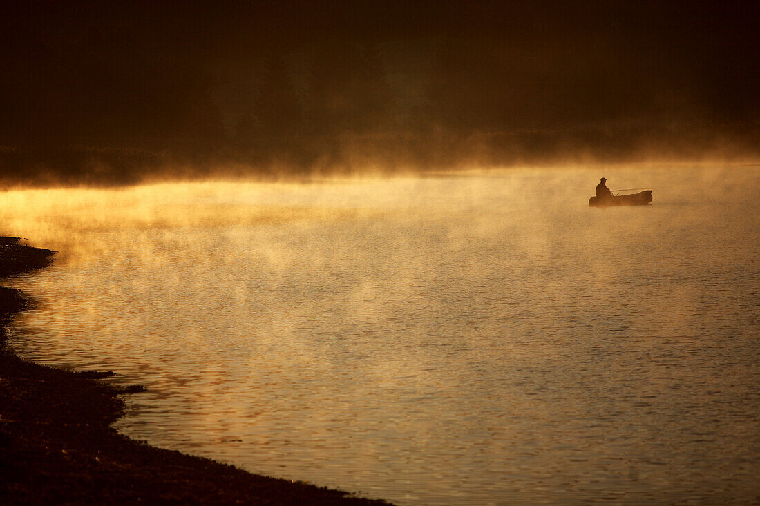 Man fishing on Lake Alpsee in the morning, Schwangau, Bavaria, Germany