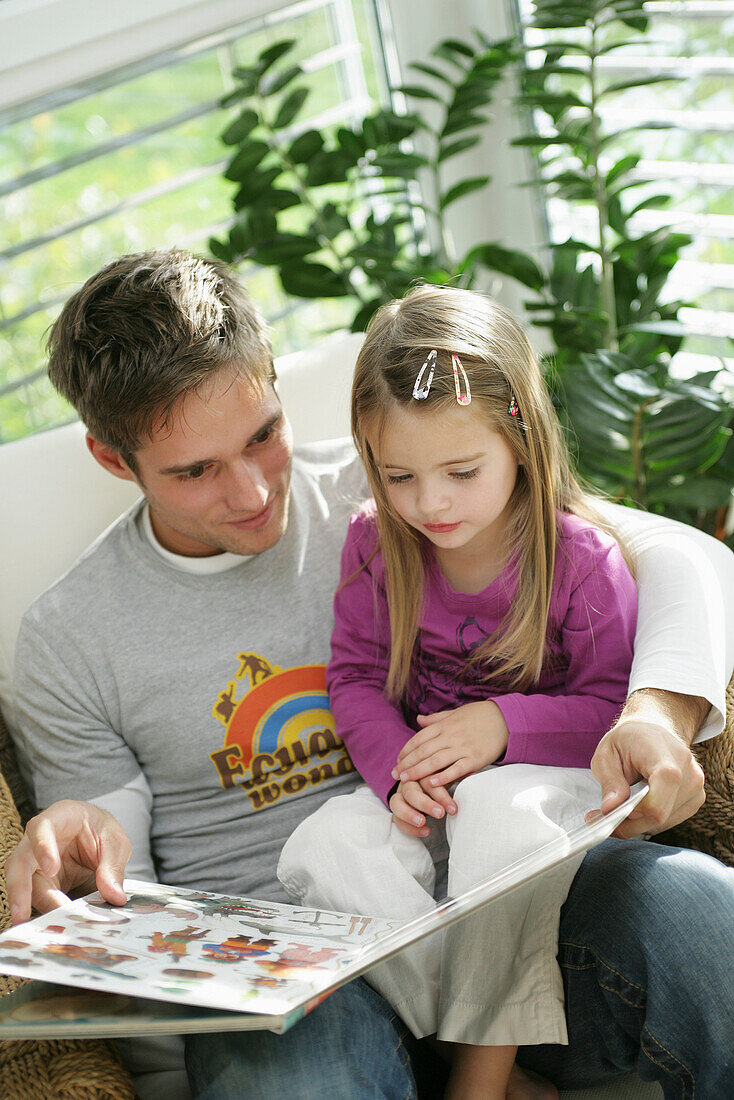 Vater und Tochter (3-4 Jahre) lesen ein Buch, München, Deutschland