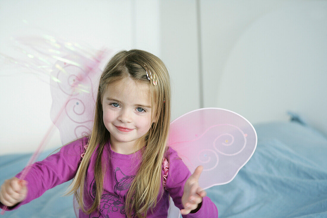 Girl (3-4 years) wearing butterfly wings holding wand, Munich, Germany