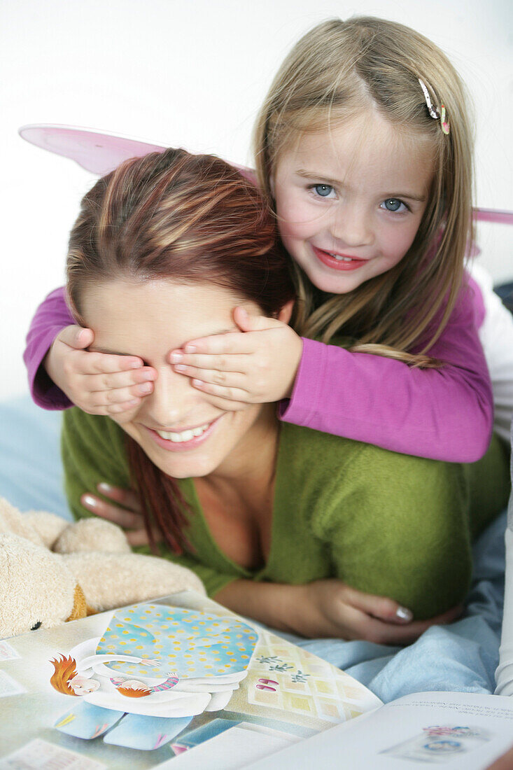 Girl (3-4 years) covering mother's eyes, Munich, Germany