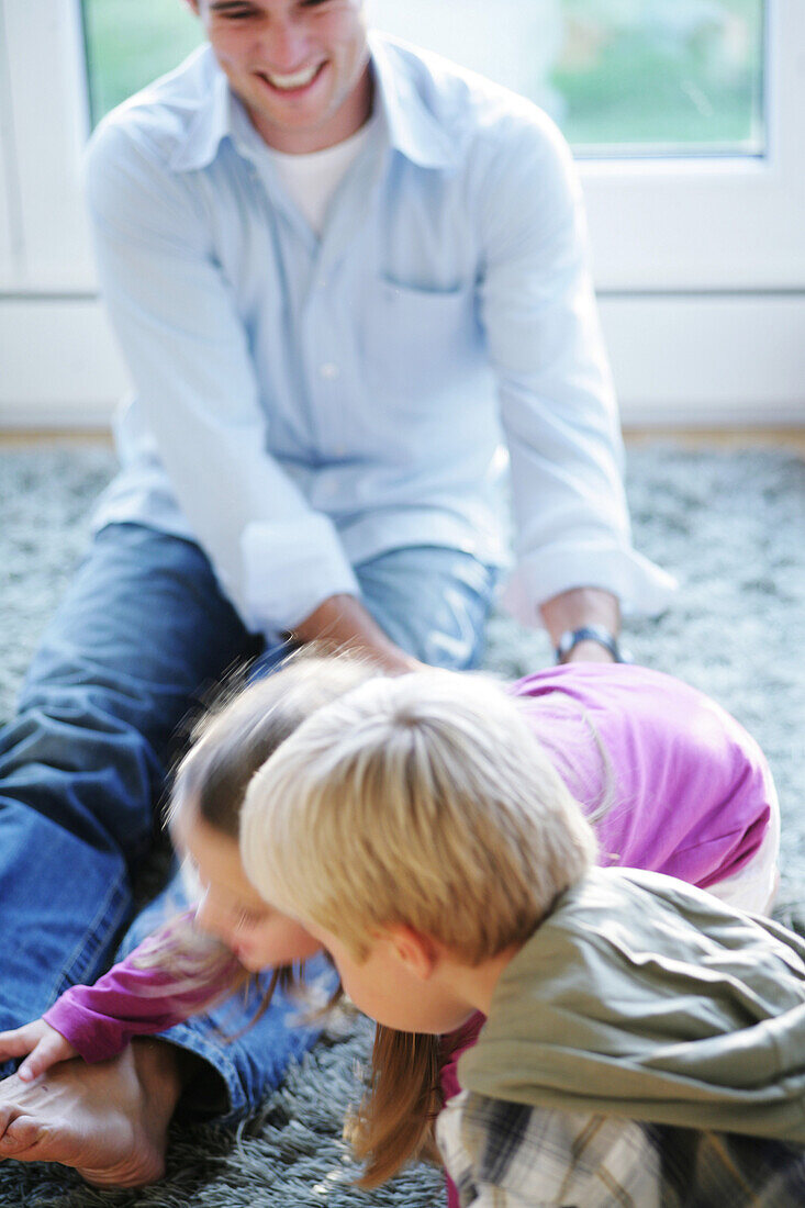 Father playing with children (2-4 years) on floor, Munich, Germany