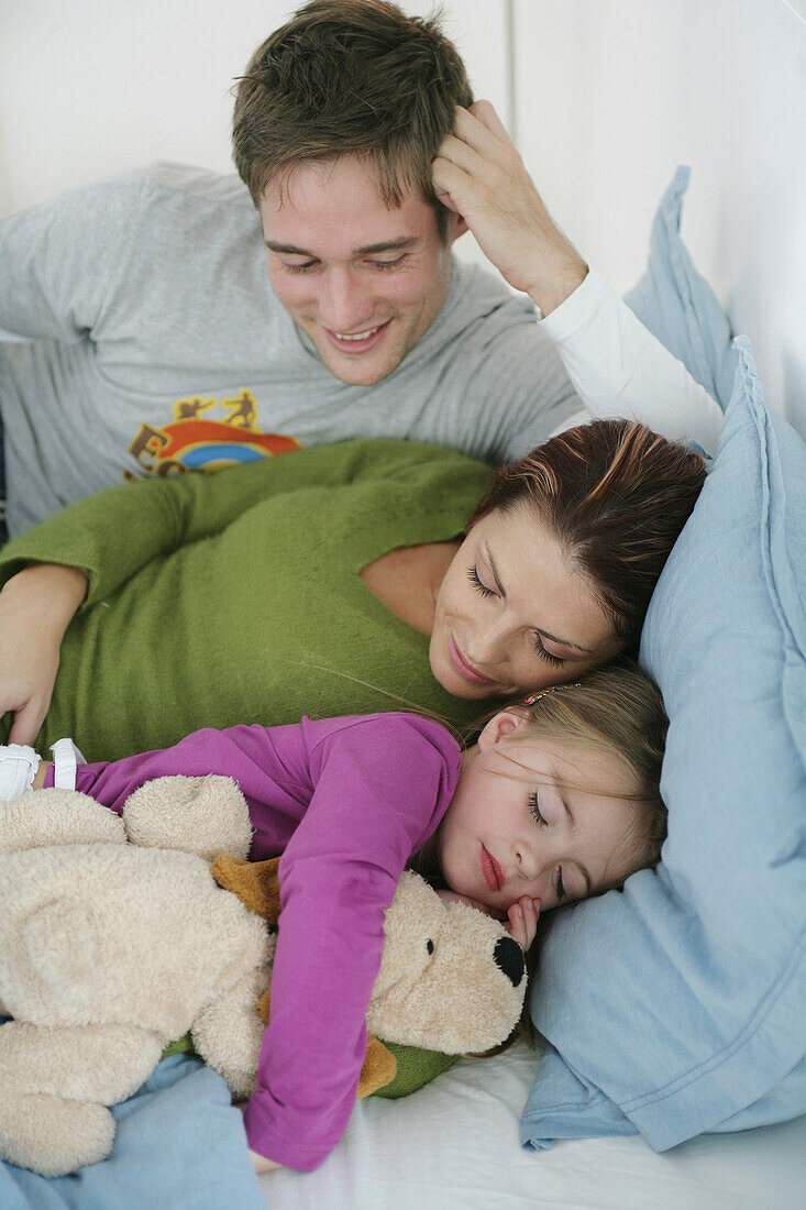 Young family lying on bed, mother and daughter sleeping, Munich, Germany