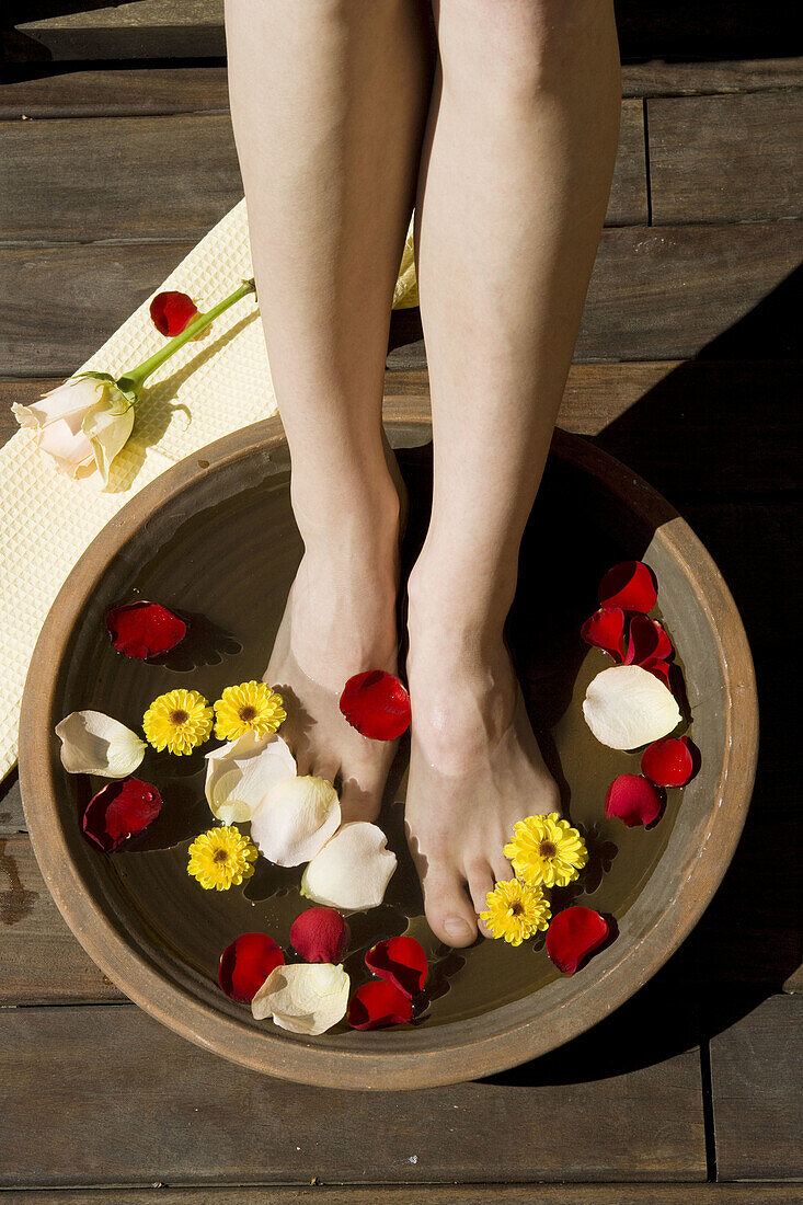 Frau beim Fußbad mit Blüten