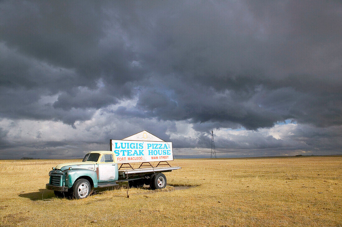 Approaching storm and truck sign for Luigi s Pizza and Steak House in autumn. Fort Macleod. Alberta, Canada