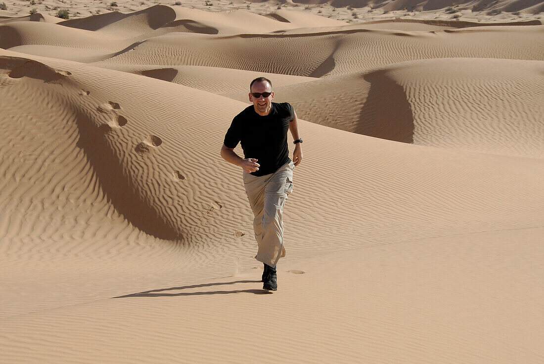 Man running through the desert, Offroad 4x4 Sahara Desert Tour, Bebel Tembain area, Sahara, Tunisia, Africa, mr