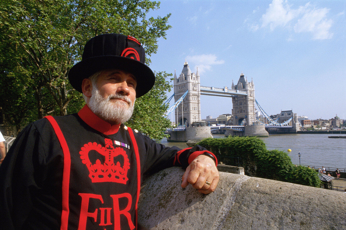 Beefeater and Tower Bridge at rear. London. England