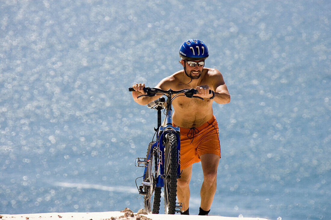 Man, mountain biker pushing mountain bike, Sandy Bay Beach, Cape Town, South Africa, Africa, mr