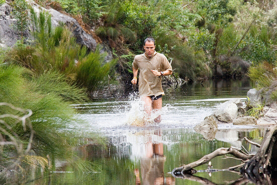 Mann läuft durch einen Fluss, Grabouw Forest Park, Westkap, Südafrika