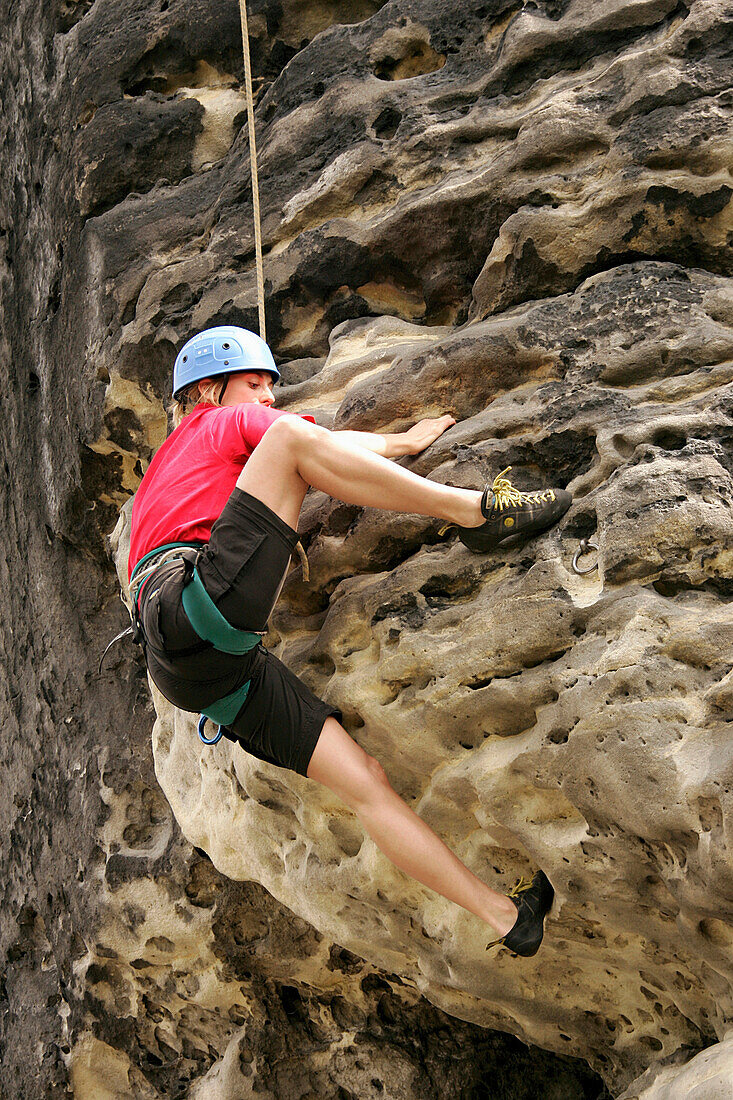 Woman climbing on sandstone rocks, Elbe Sandstone Mountains, near Rathen, Saxony, Germany