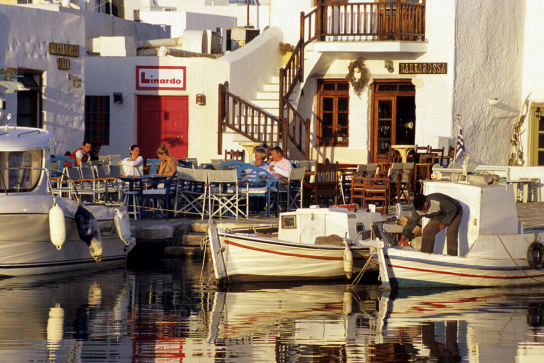Fishing boats docked next to taverns on the inner harbour of the town of Naoussa. Paros. Cyclades Islands, Greece